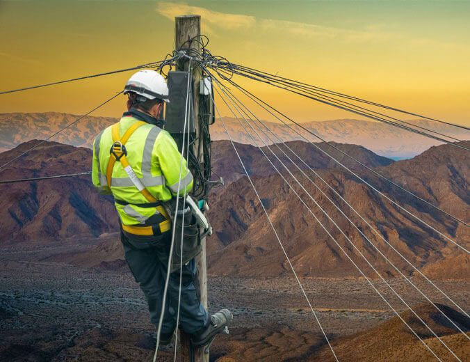 Lineman in a remote desert landscape, fixing a telephone line